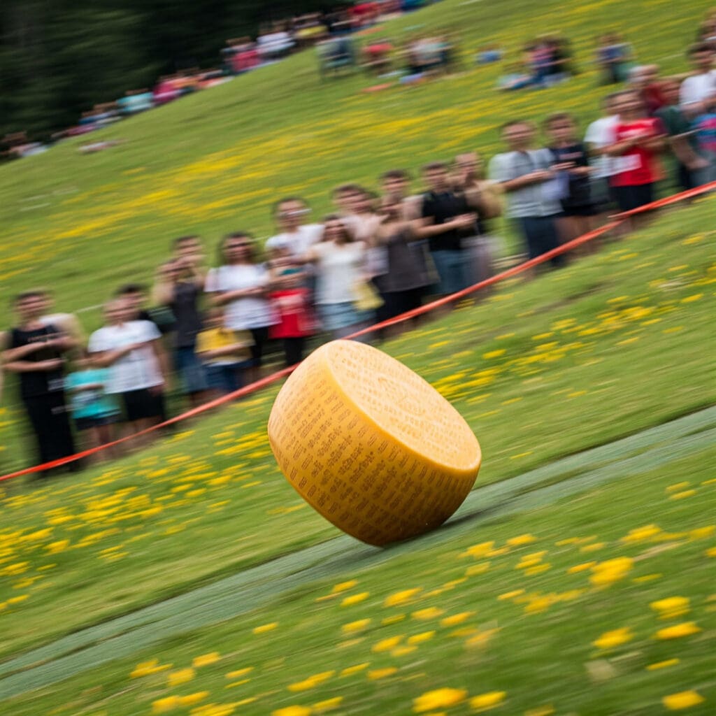 Un grupo de hombres valientes persiguen cuesta abajo una rueda de queso.