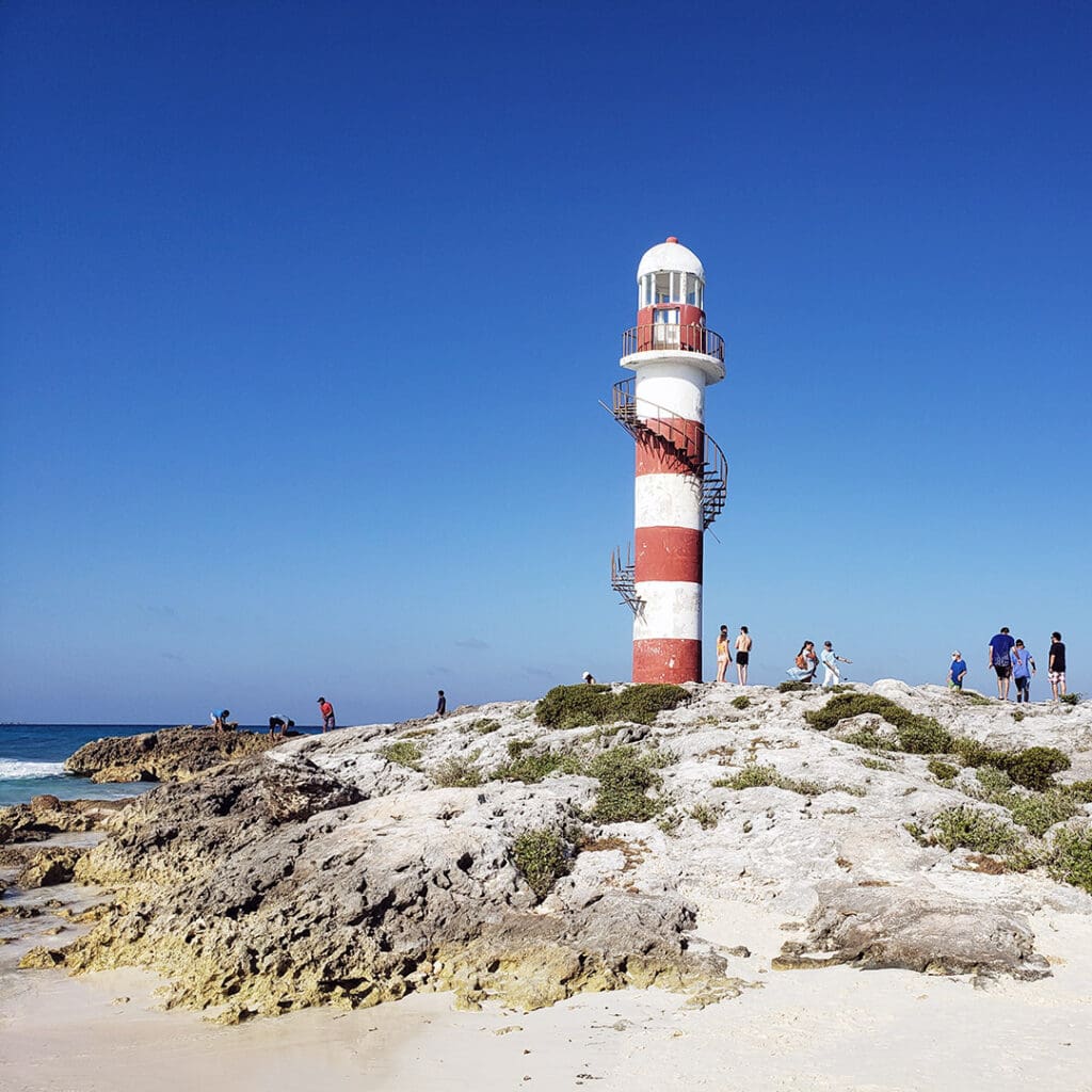 El faro blanco y rojo marca la entrada a Punta Cancún.